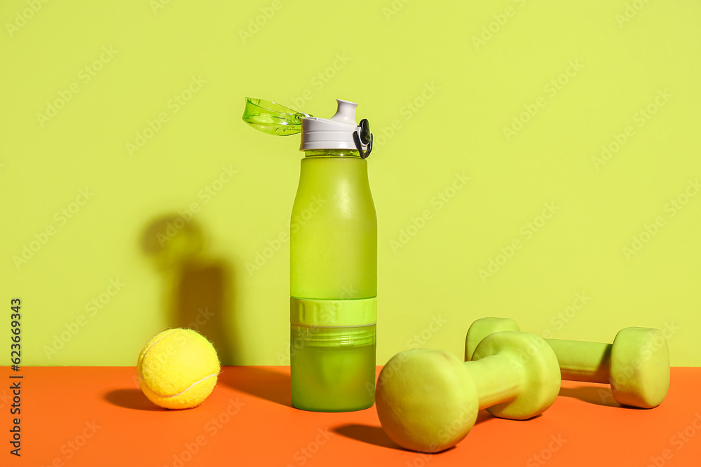 Bottle of water, dumbbells and tennis ball on color background