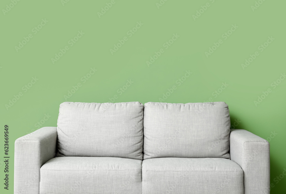 Cozy grey sofa near green wall