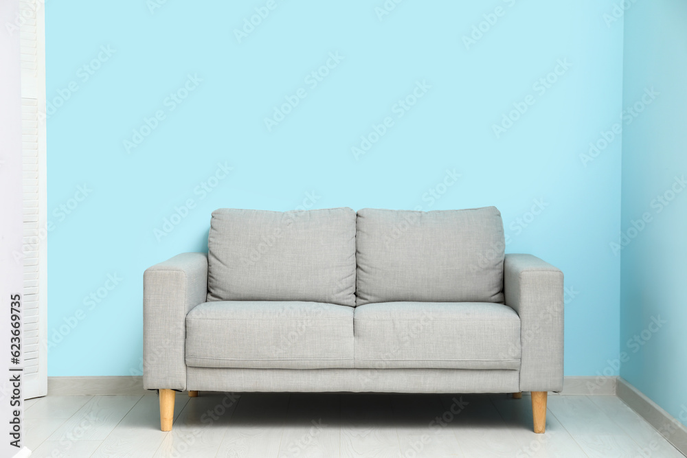 Cozy grey sofa near blue wall