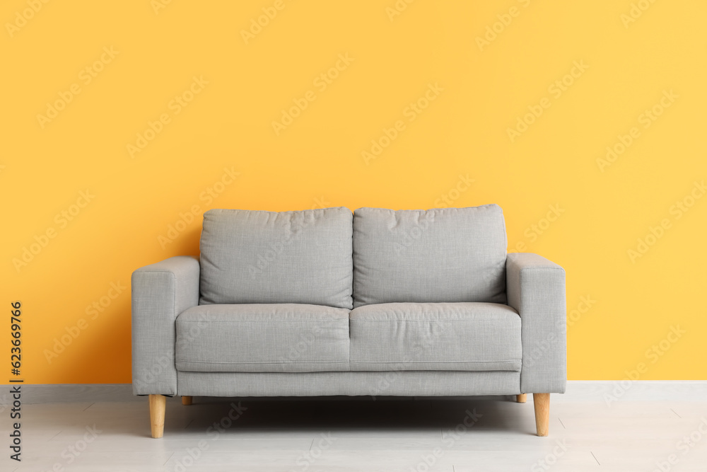 Cozy grey sofa near orange wall