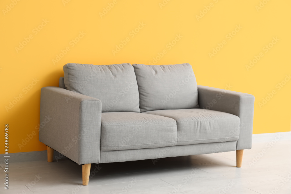 Cozy grey sofa near orange wall