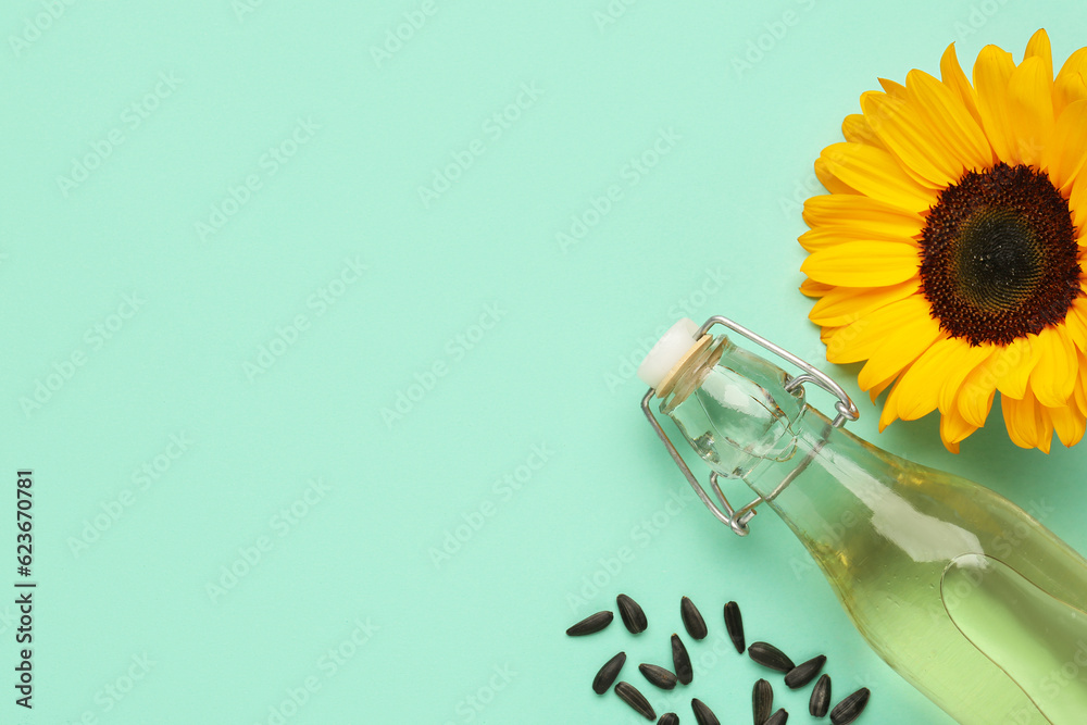 Bottle of oil, sunflower and seeds on green background