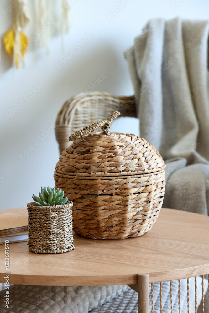 Wicker basket on coffee table near rattan armchair in living room, closeup