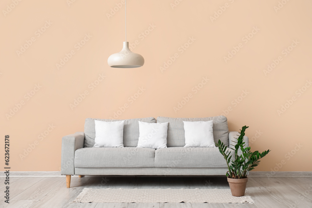 Grey sofa with white pillows near beige wall