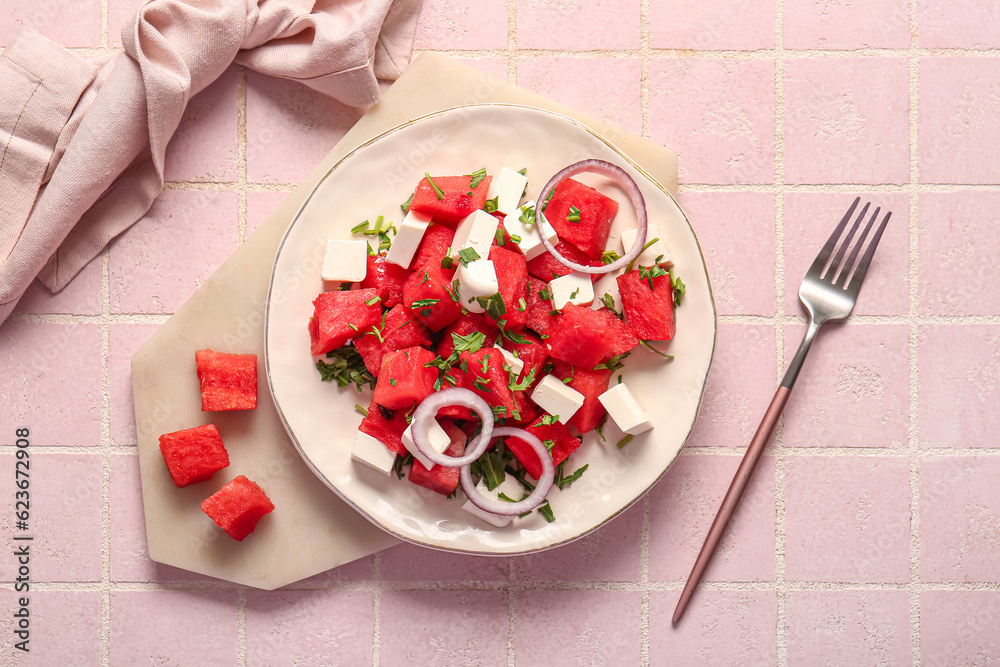 Plate of tasty watermelon salad on pink tile background