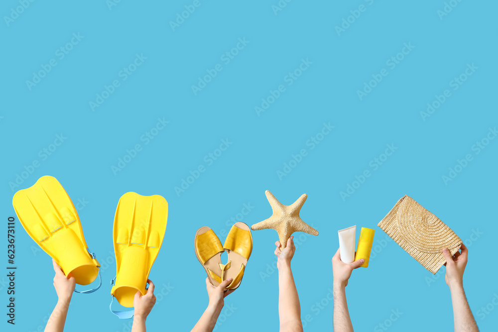 Many hands with beach accessories on blue background