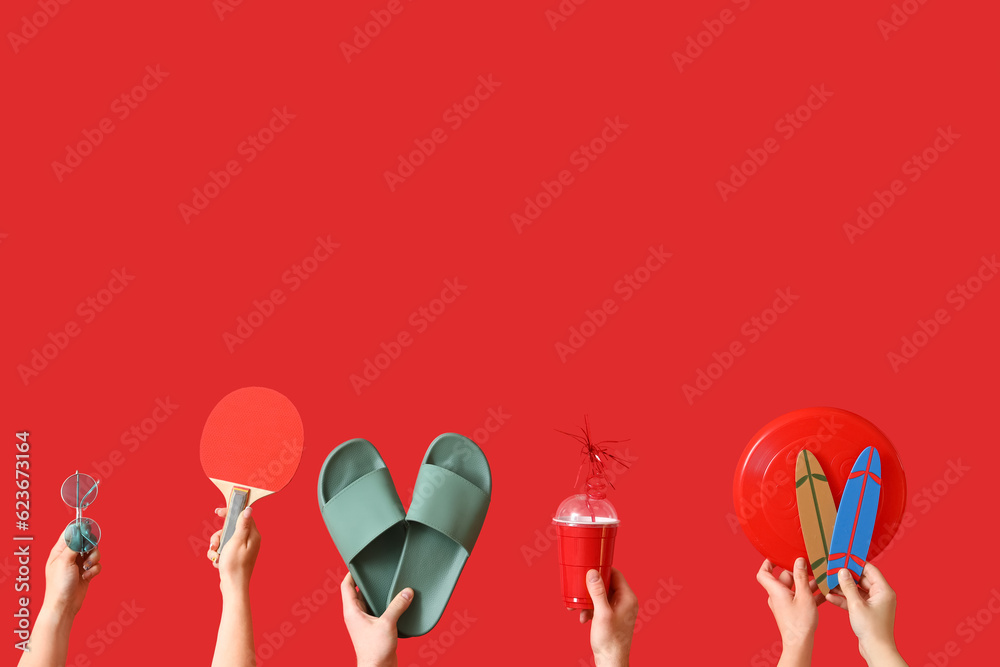 Many hands with beach accessories on red background