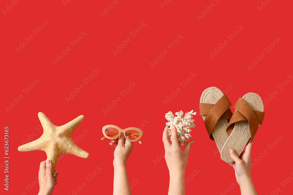 Many hands with beach accessories on red background