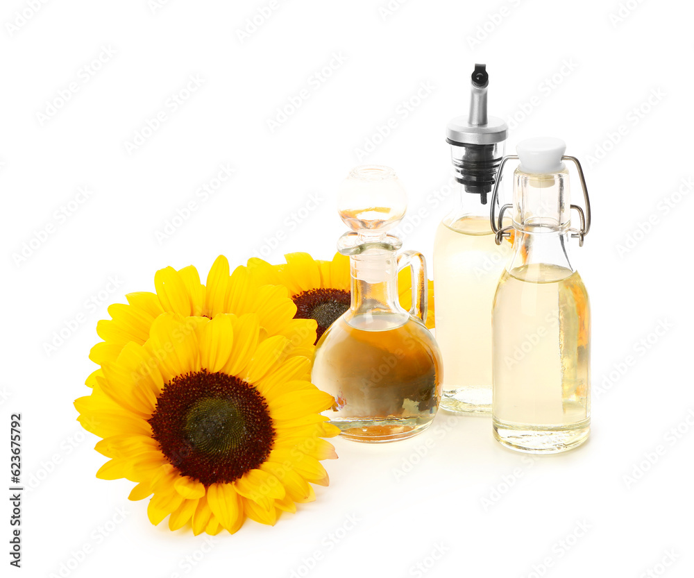 Bottles and decanter with sunflower oil on white background