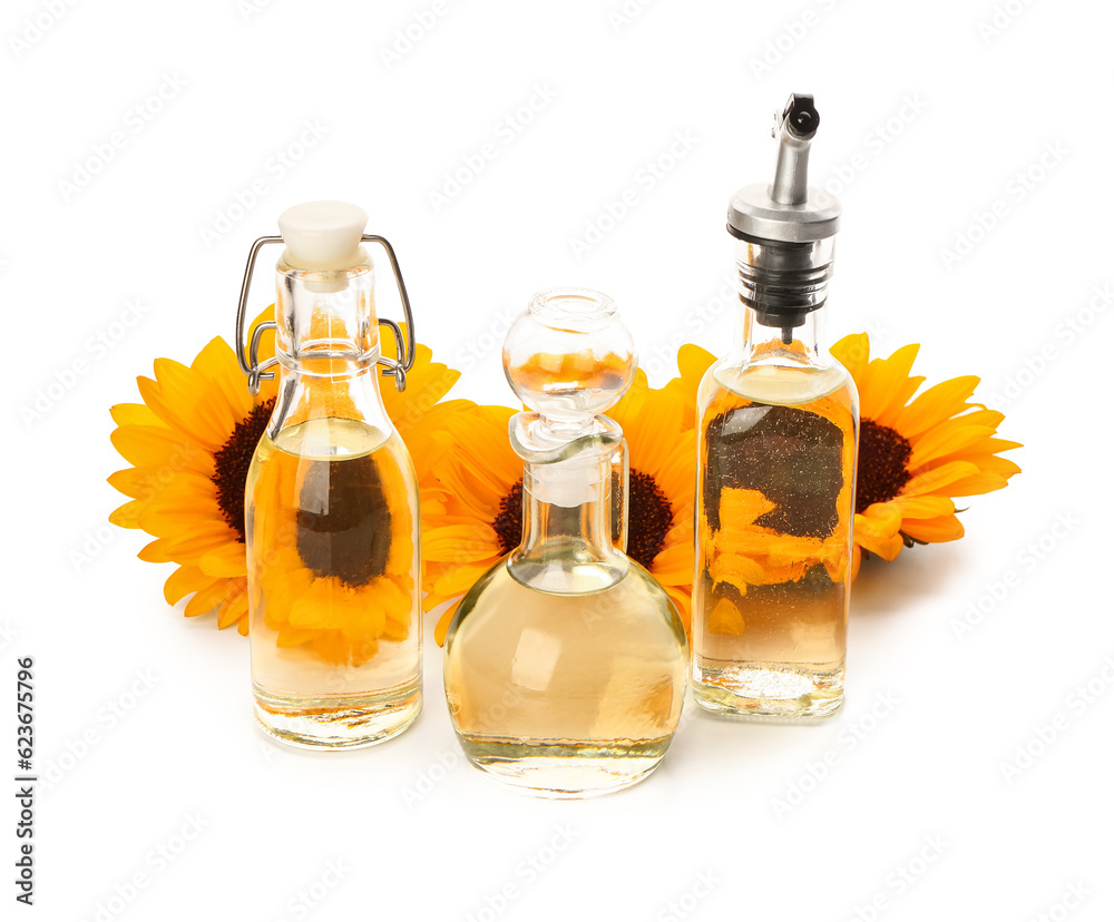 Bottles and decanter with sunflower oil on white background