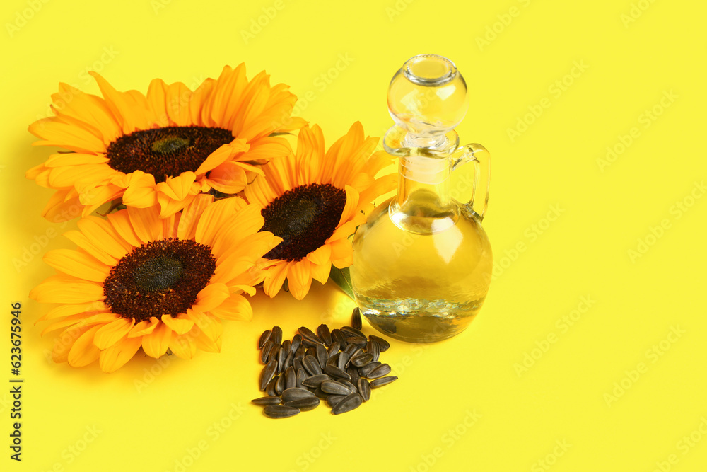 Sunflowers, seeds and decanter of oil on yellow background