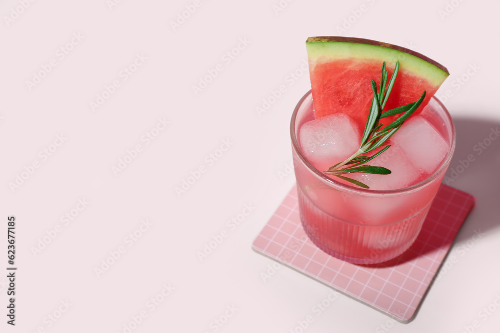 Glass of tasty watermelon cocktail on pale pink background