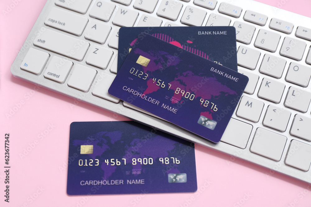 Keyboard with credit cards on pink background