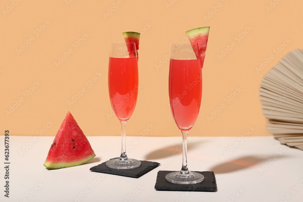 Glasses of tasty watermelon cocktail on white table near orange wall