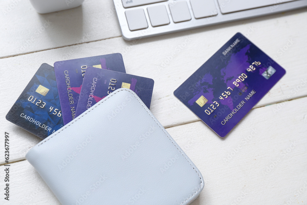 Keyboard with wallet and credit cards on white wooden background