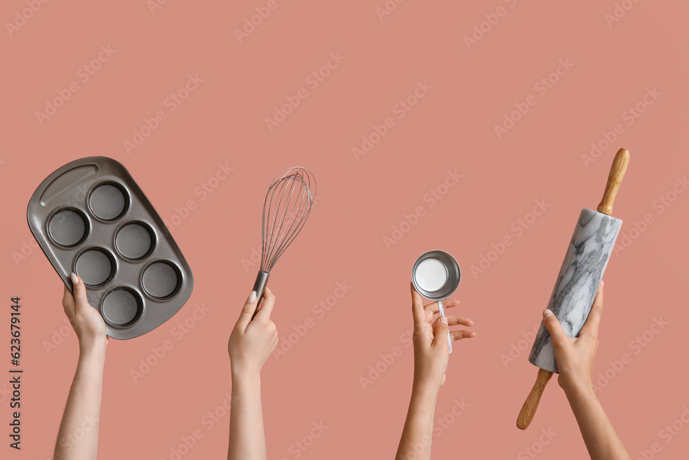 Female hands with baking utensils on pink background