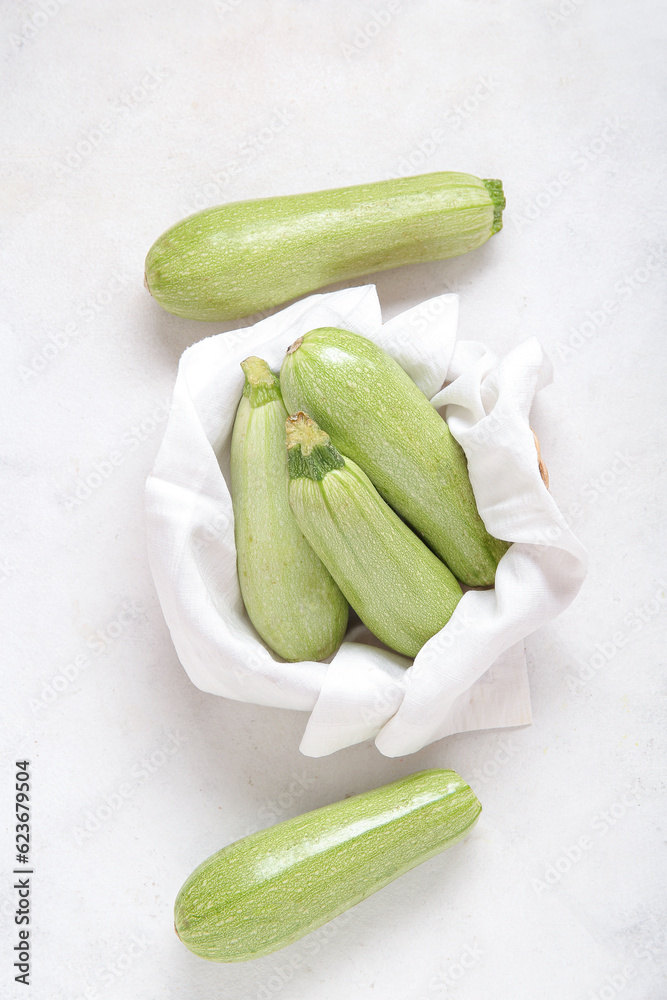 Bowl with fresh green zucchini on light background