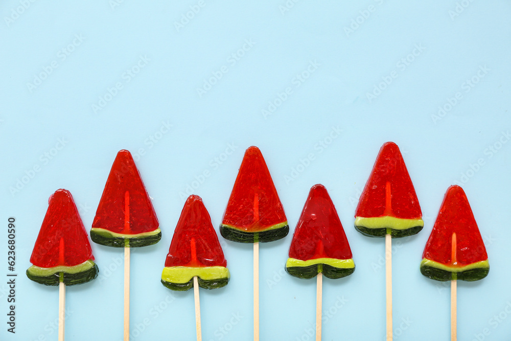 Lollipops in shape of watermelon slice on blue background