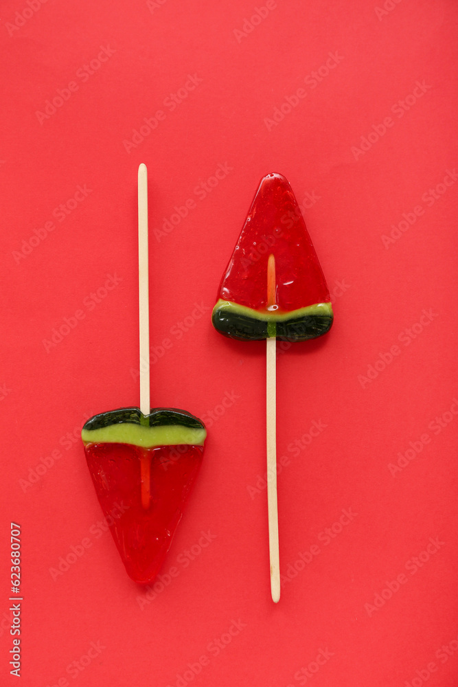 Lollipops in shape of watermelon slice on red background