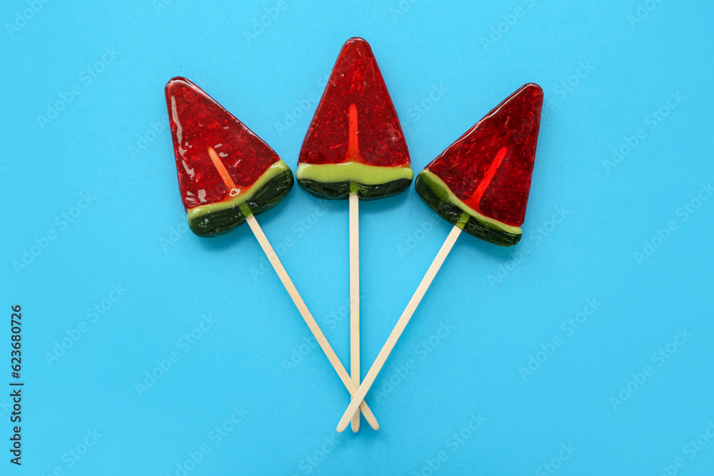 Lollipops in shape of watermelon slice on blue background