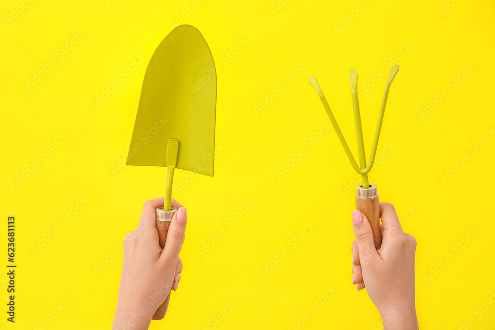 Woman with gardening rake and shovel on yellow background