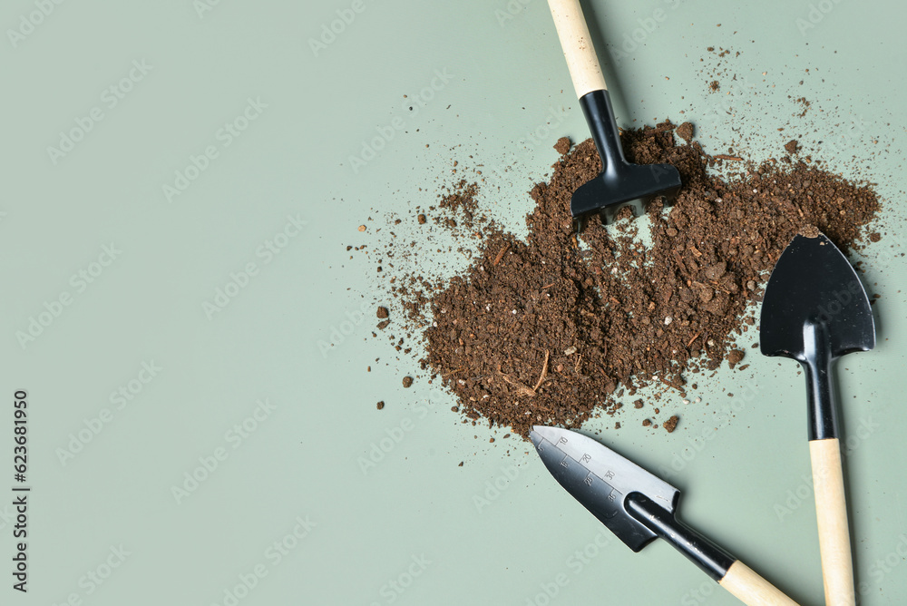 Gardening rake, shovels and soil on green background