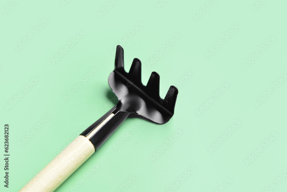 Gardening rake on green background