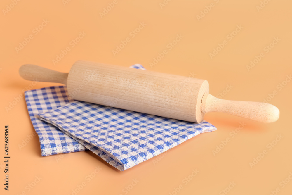 Wooden rolling pin and clean napkins on color background