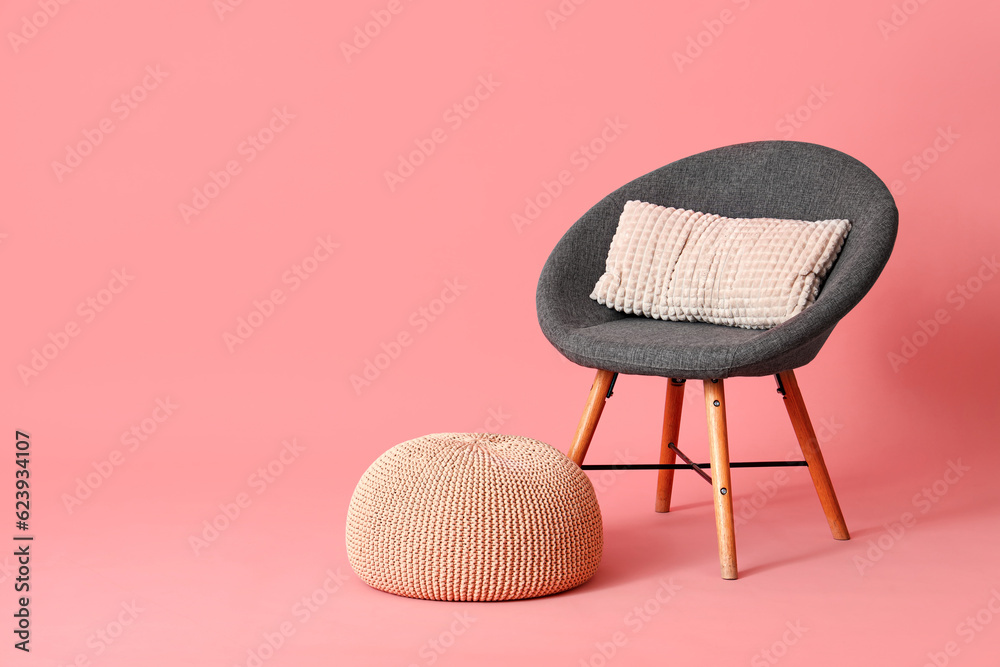 Grey armchair with cushion and pouf on pink background