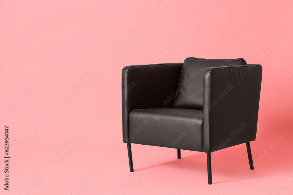 Black leather armchair on pink background