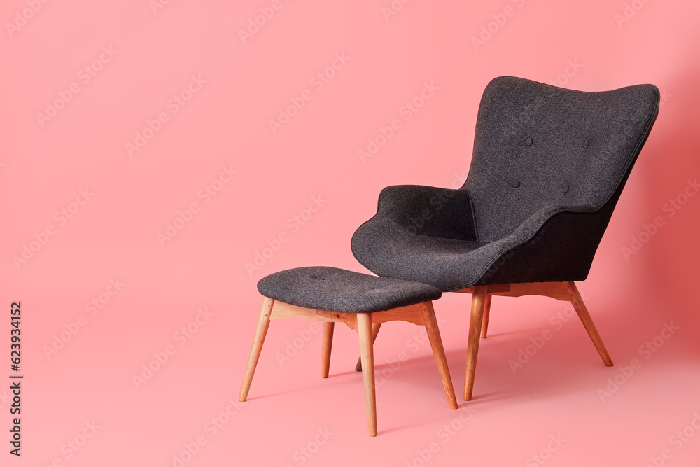 Black armchair with ottoman on pink background