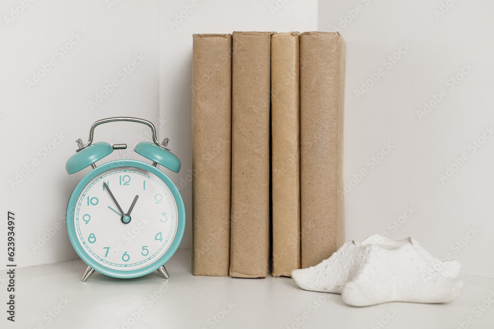 Vintage alarm clock with books on shelf in room