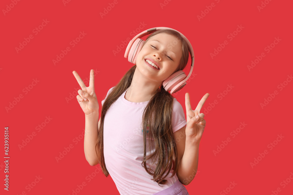 Little girl in headphones dancing on red background