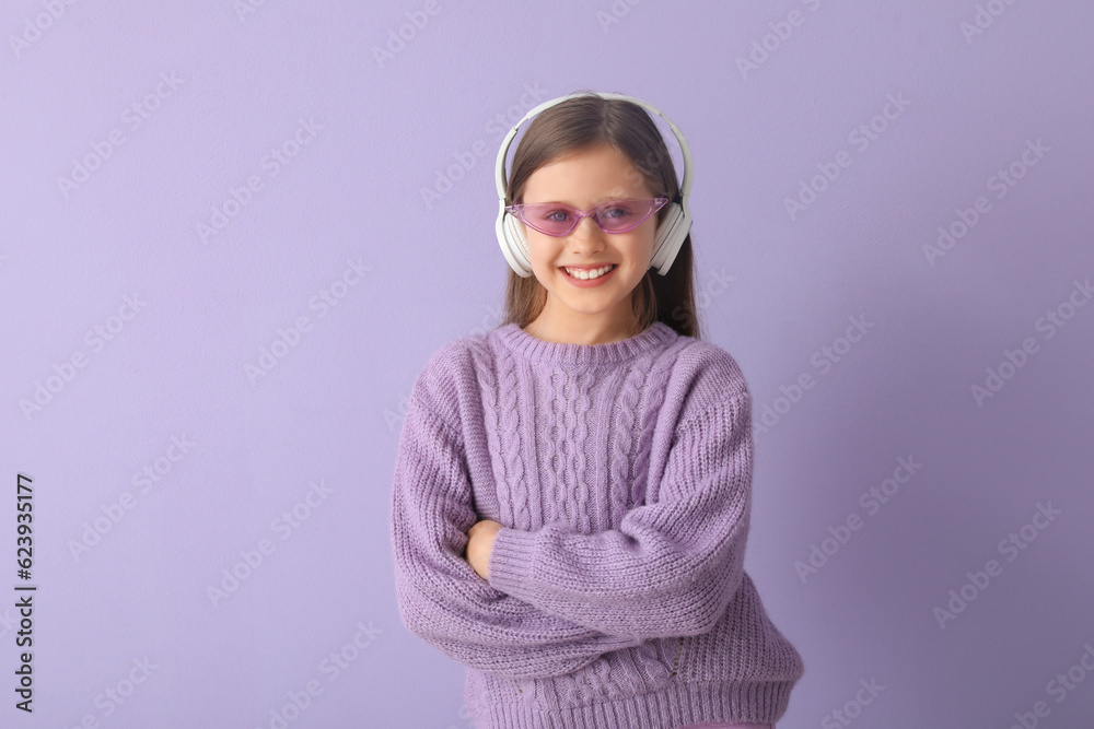 Little girl in headphones on lilac background