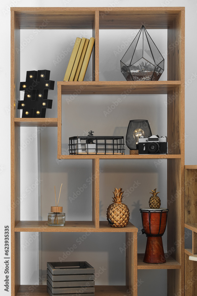 Shelving unit with glowing lamps, books and decor in room