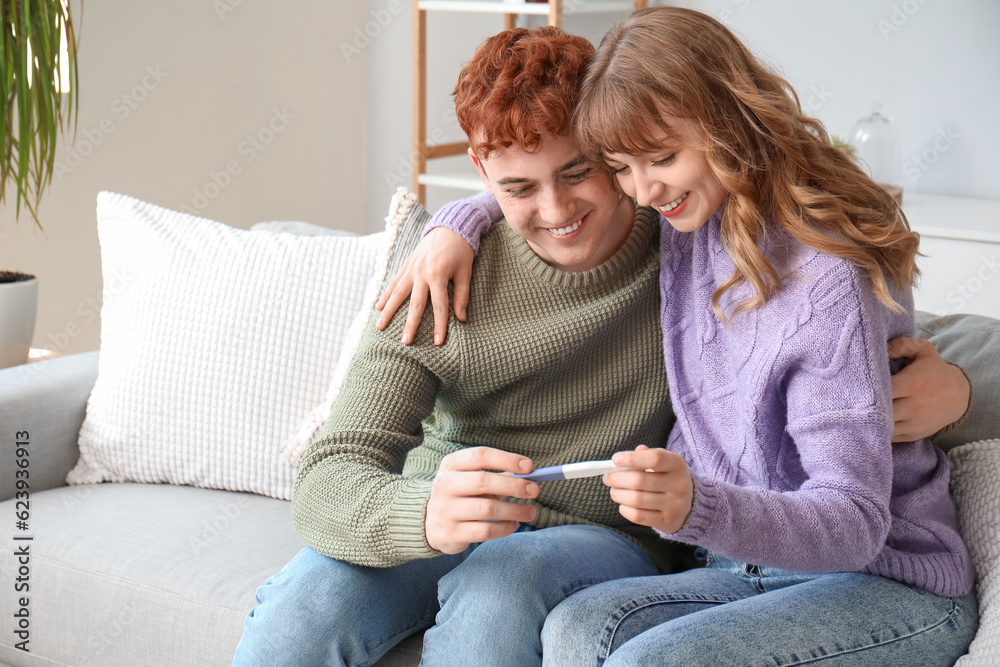 Happy young couple with pregnancy test hugging at home