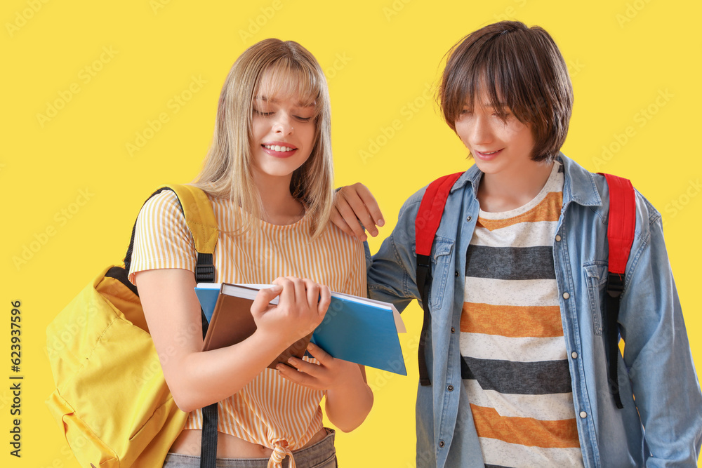 Teenage students with books on yellow background