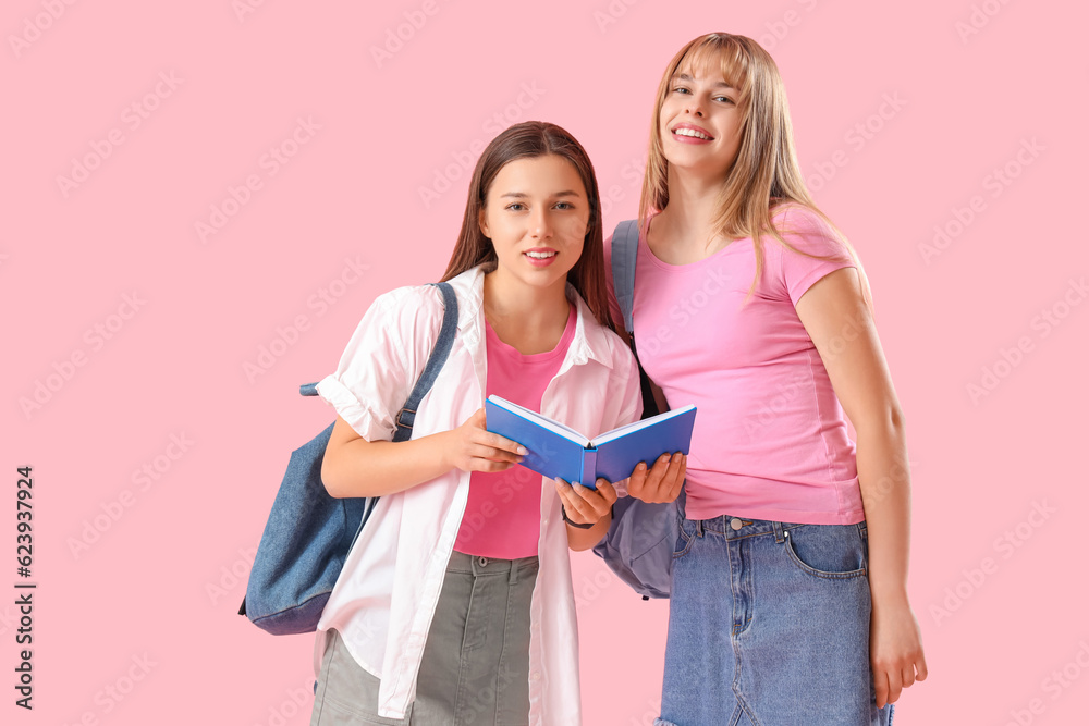 Female students reading book on pink background