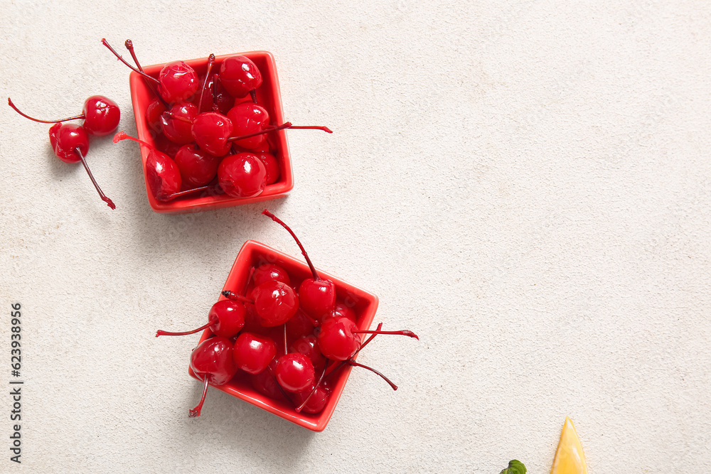 Bowls of tasty maraschino cherries on light background