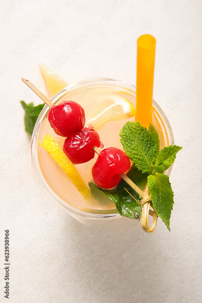 Glass of tasty cocktail with maraschino cherries on light background