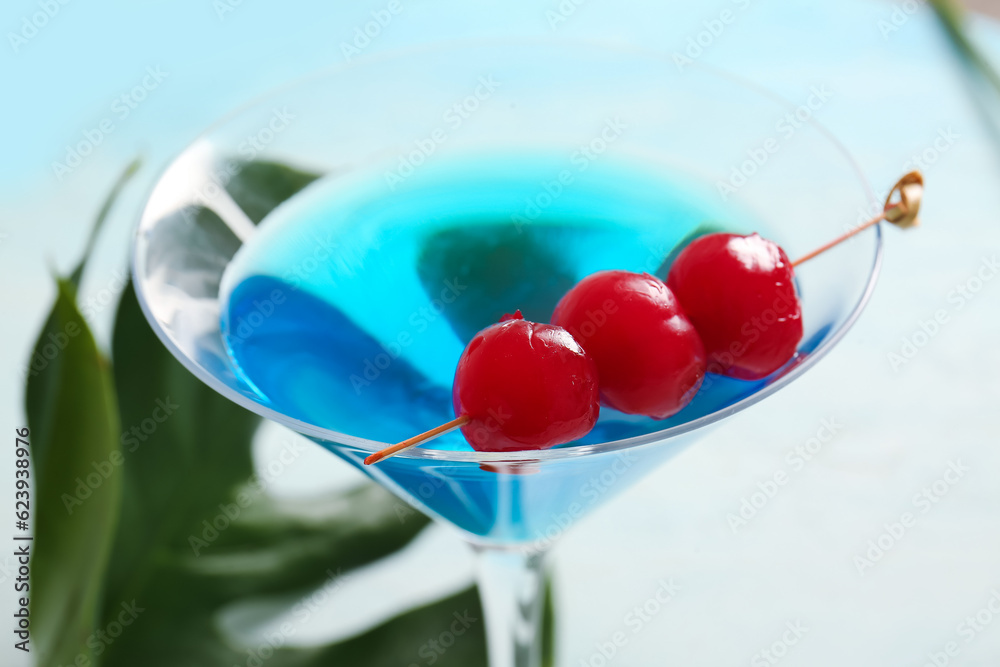 Glass of tasty cocktail with maraschino cherries on light background