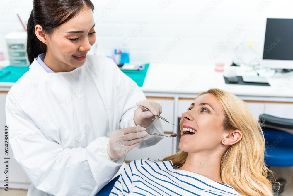 Female dentist examine tooth to Caucasian girl at dental health clinic. 