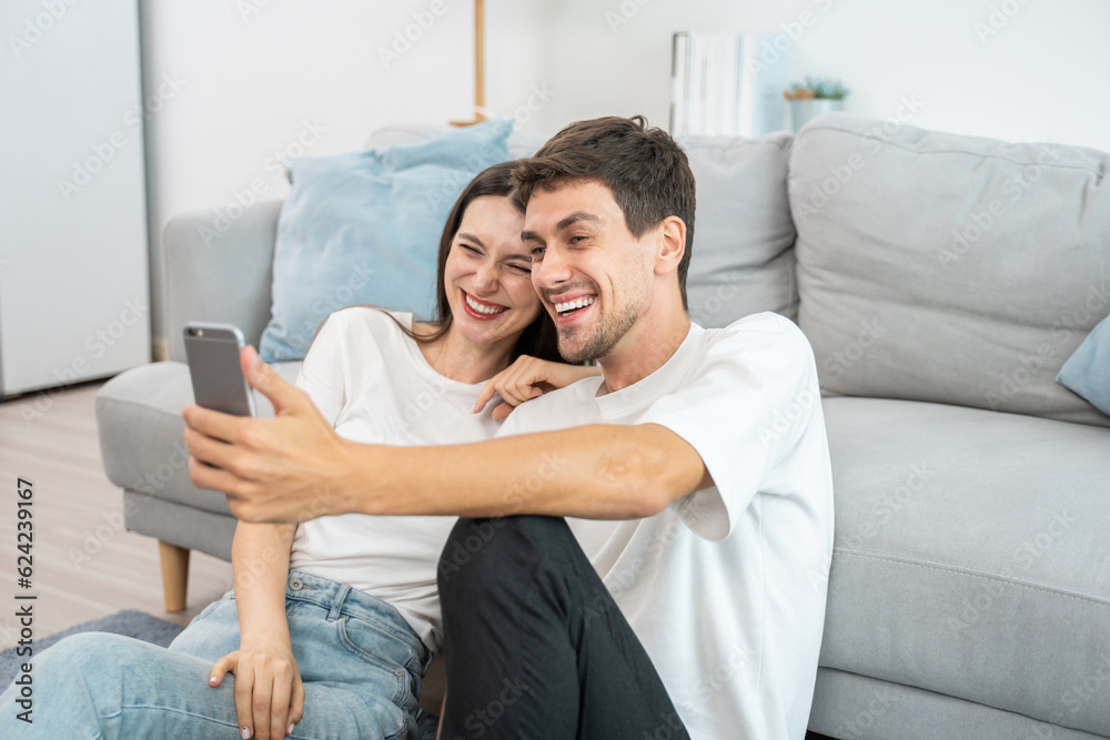 Caucasian attractive couple use mobile phone video call in living room. 