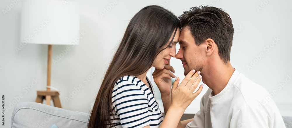 Caucasian young man and woman kissing each other in living room at home. 