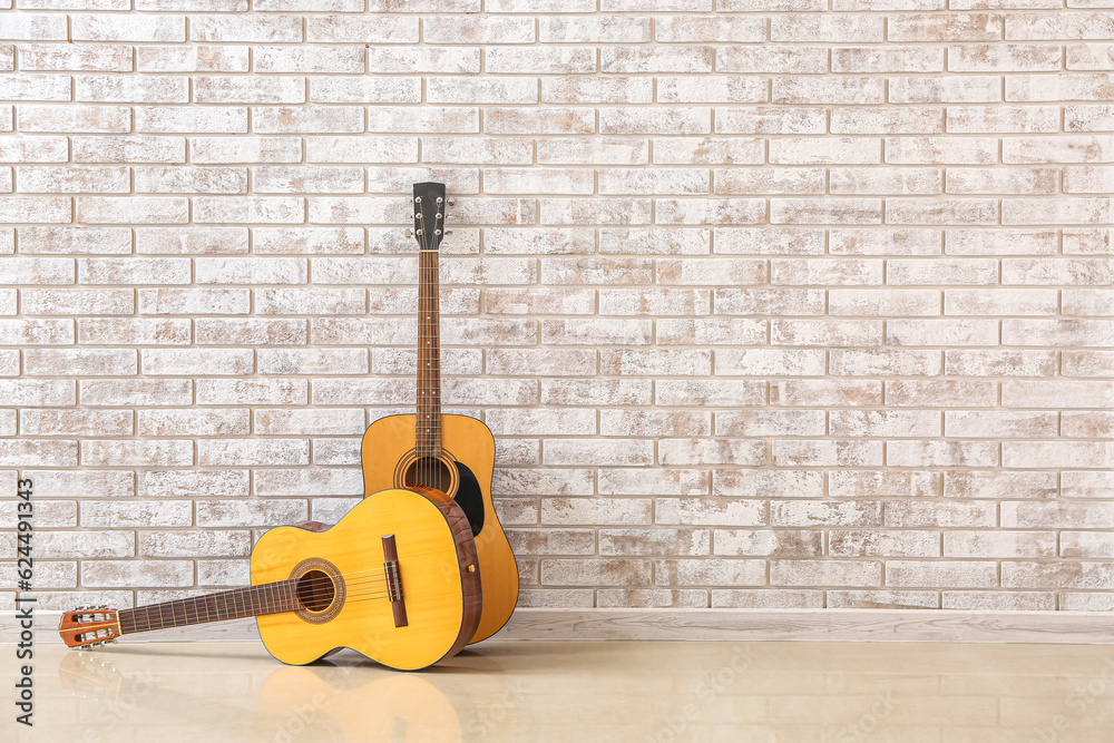 Two guitars near brick wall