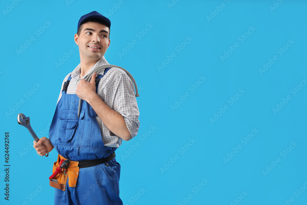 Young male plumber with tools on blue background