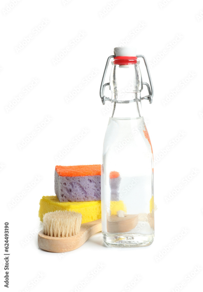 Bottle of vinegar, brush and sponges on white background