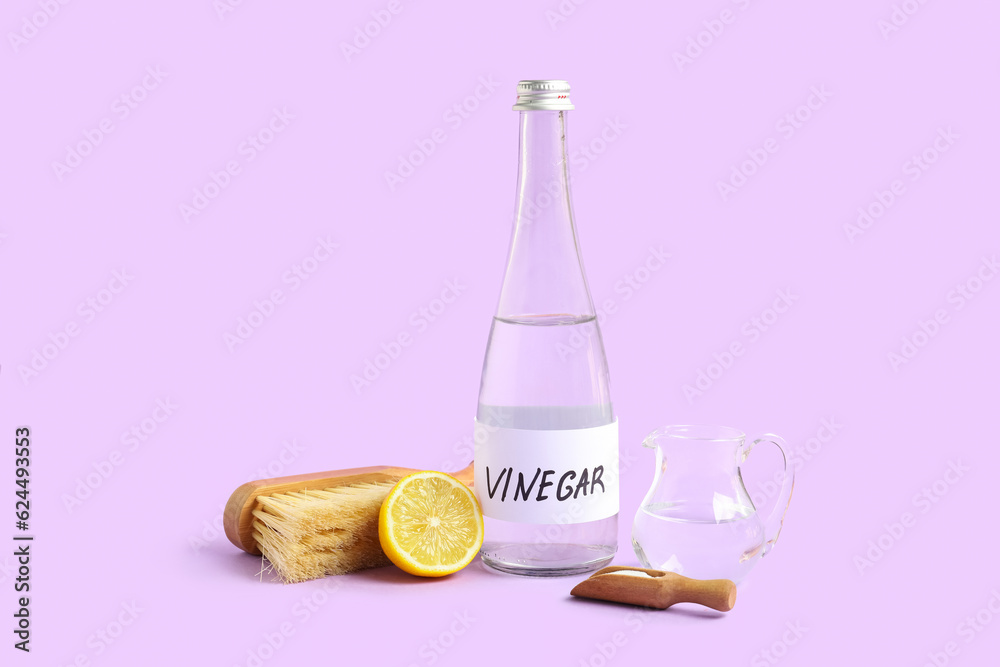 Bottle of vinegar, brush, baking soda and lemon on lilac background