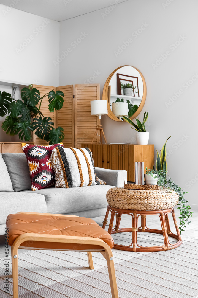 Interior of light living room with sofa, table and Monstera houseplant