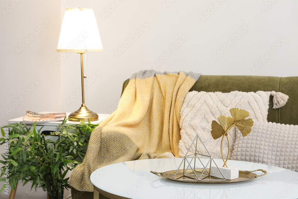 Interior of stylish living room with cozy green sofa, coffee table and glowing lamp